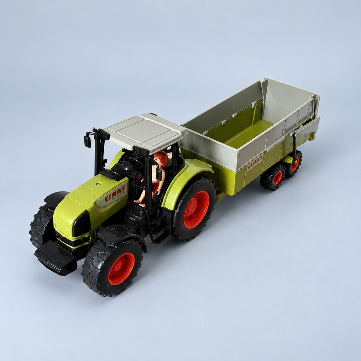 Zielony zabawkowy traktor CLAAS z przyczepą — aranżacja poglądowa AI na szaroniebieskim tle