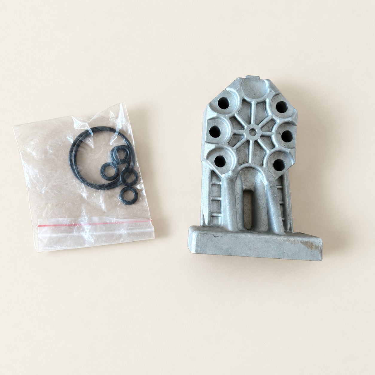Metalowy element hydrauliczny z uszczelkami — aranżacja poglądowa AI na jasnym tle