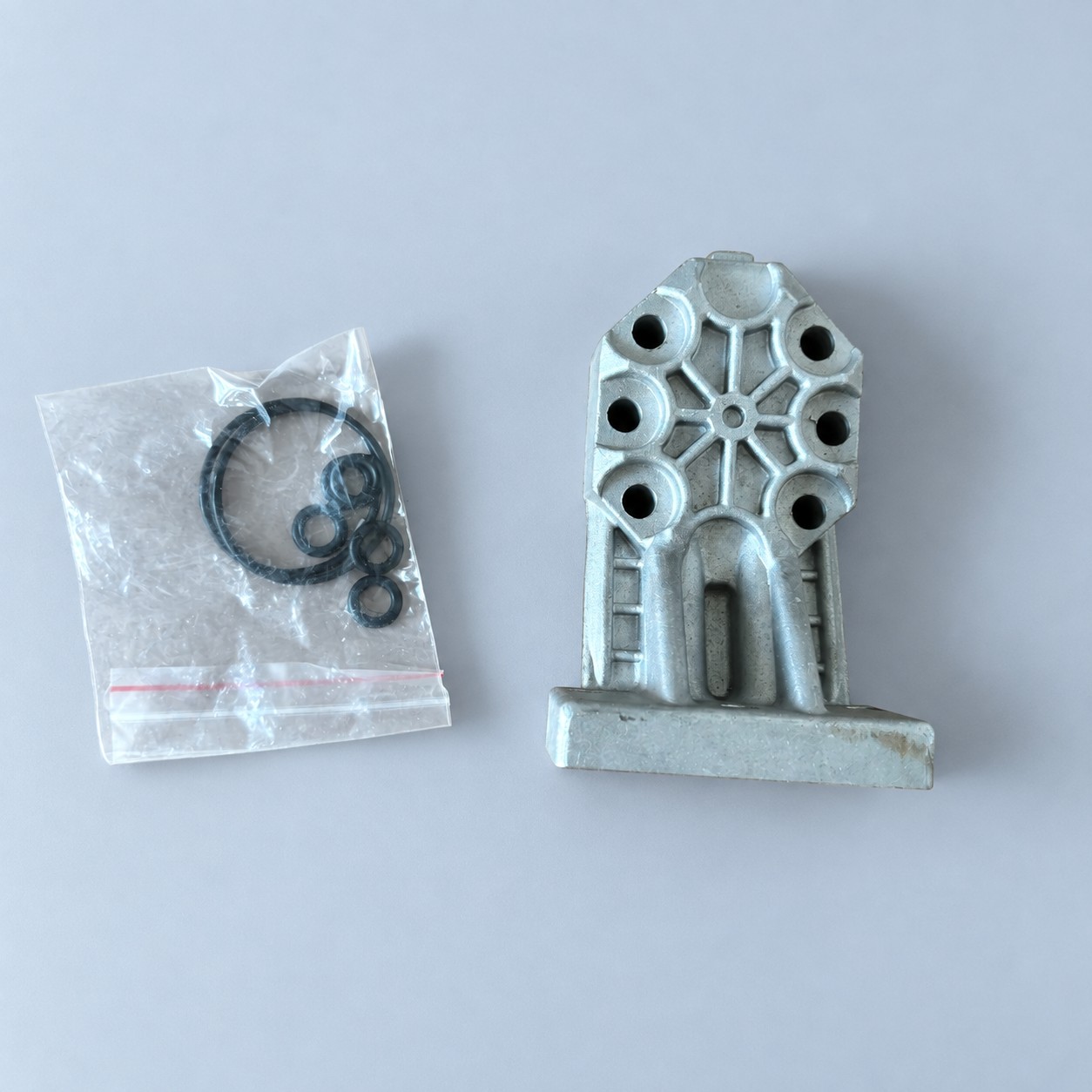 Metalowy element hydrauliczny z uszczelkami — aranżacja poglądowa AI na szaroniebieskim tle
