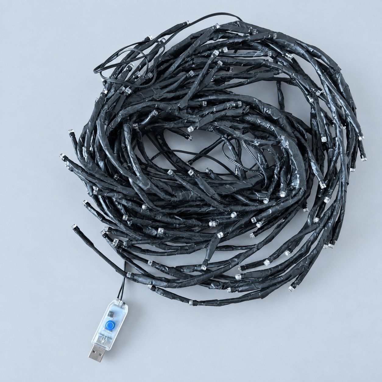 Zwinięty czarny łańcuch lampek USB — aranżacja poglądowa AI na szaroniebieskim tle