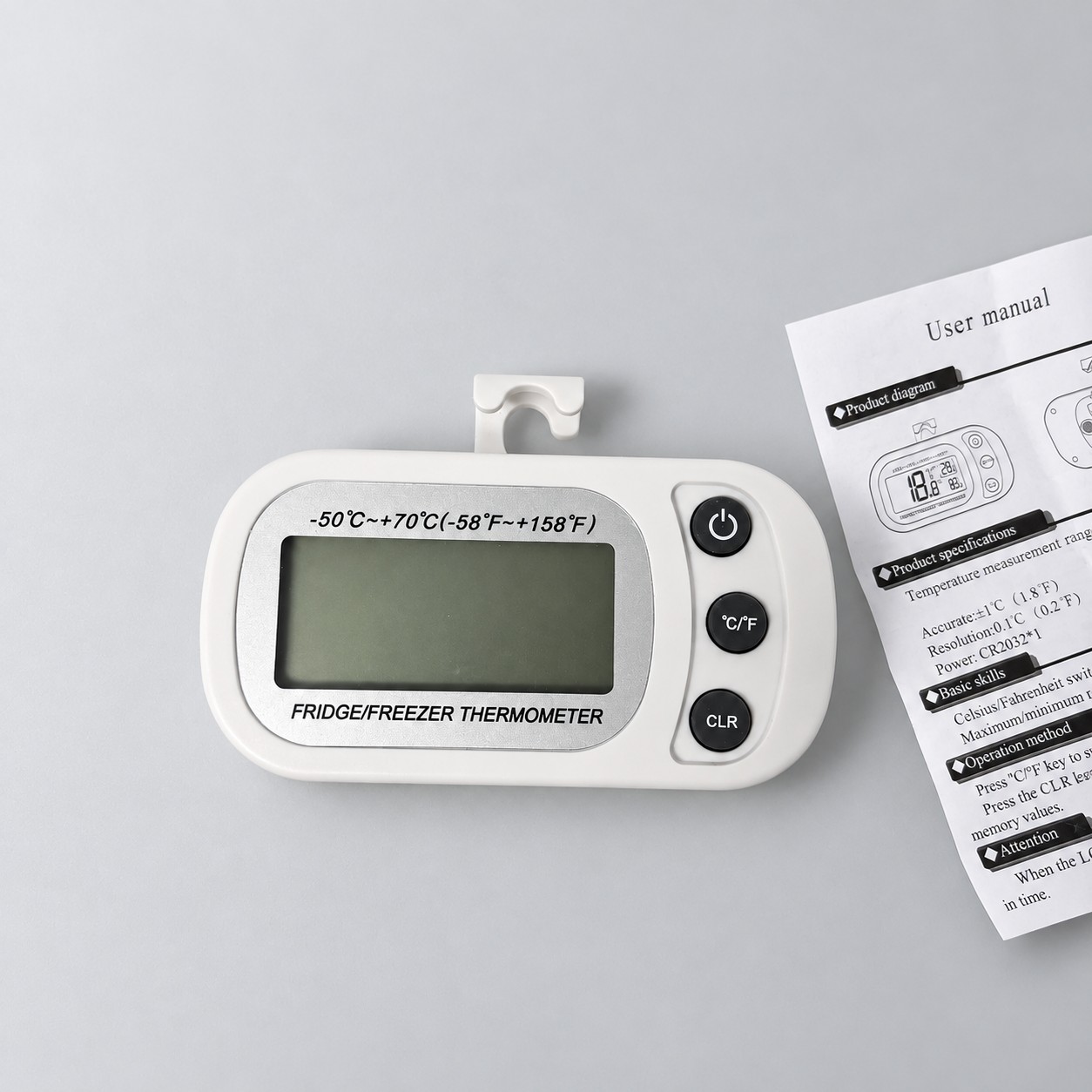 Biały termometr elektroniczny — aranżacja poglądowa AI na szaroniebieskim tle