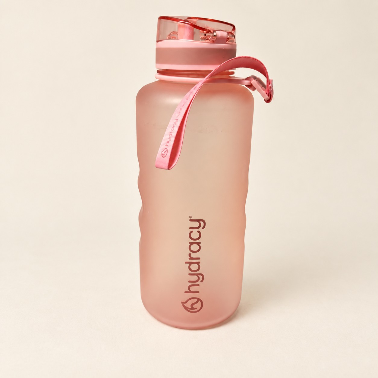 Różowa butelka Hydracy — aranżacja poglądowa AI na jasnym tle