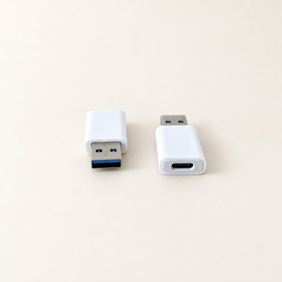 Dwa białe adaptery USB na kremowym tle.