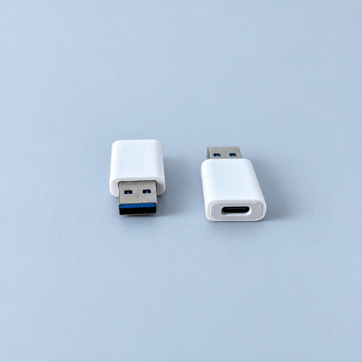 Dwa białe adaptery USB — aranżacja poglądowa AI na szaroniebieskim tle