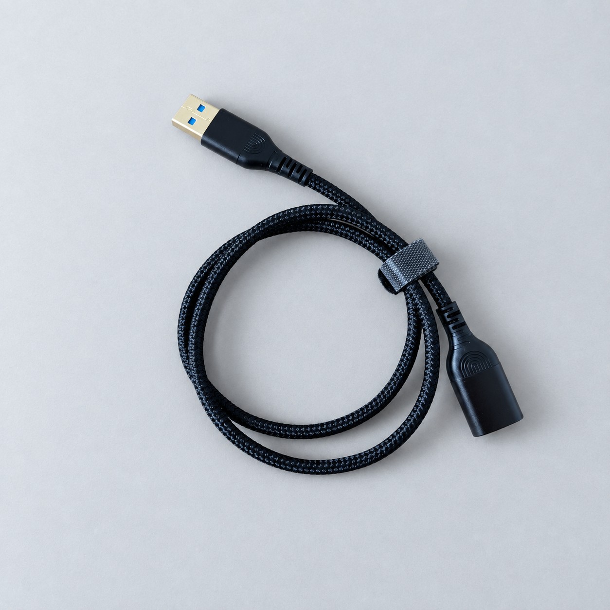 Czarny przedłużacz USB w oplocie — aranżacja poglądowa AI na szaroniebieskim tle