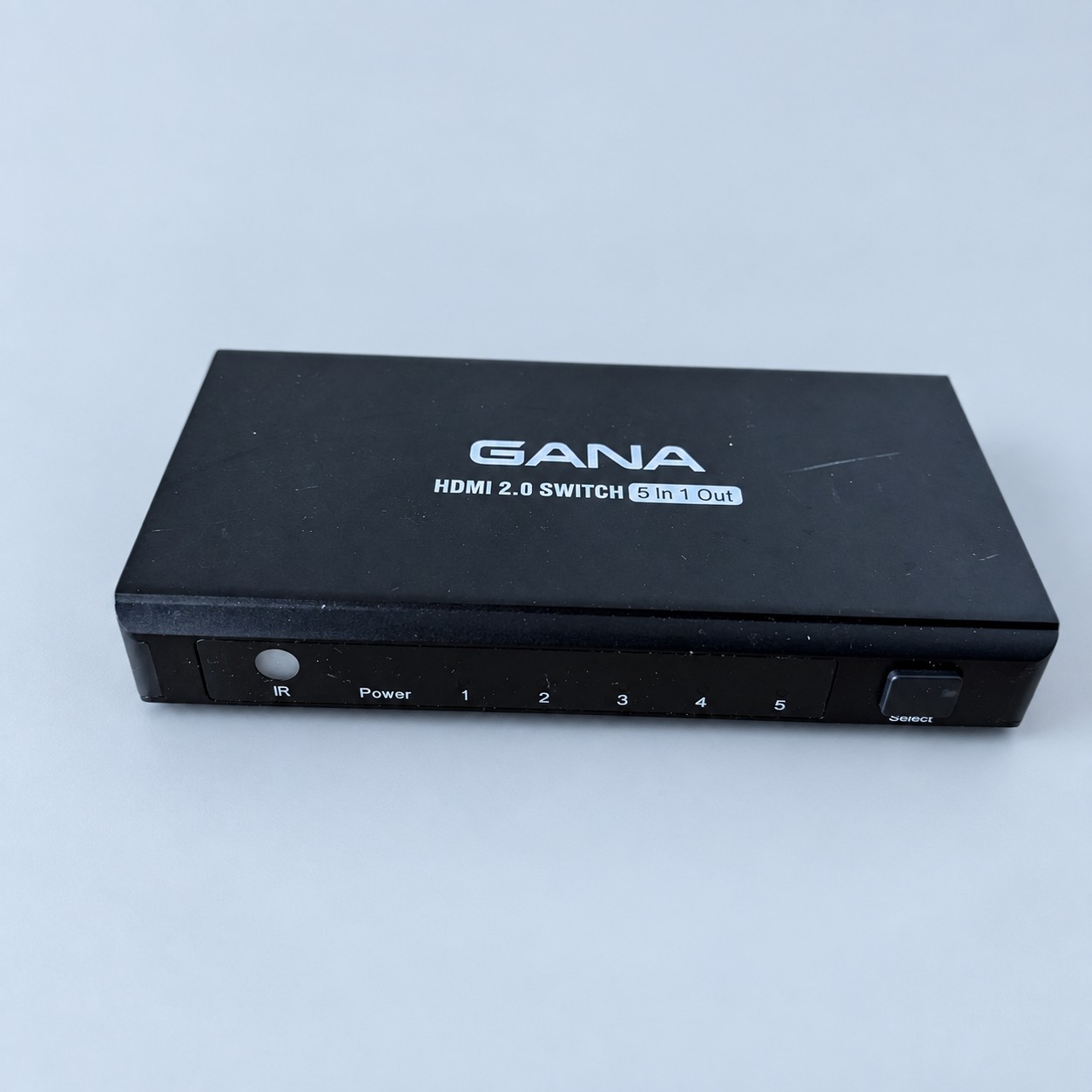Przełącznik HDMI z pilotem — aranżacja poglądowa AI na szaroniebieskim tle