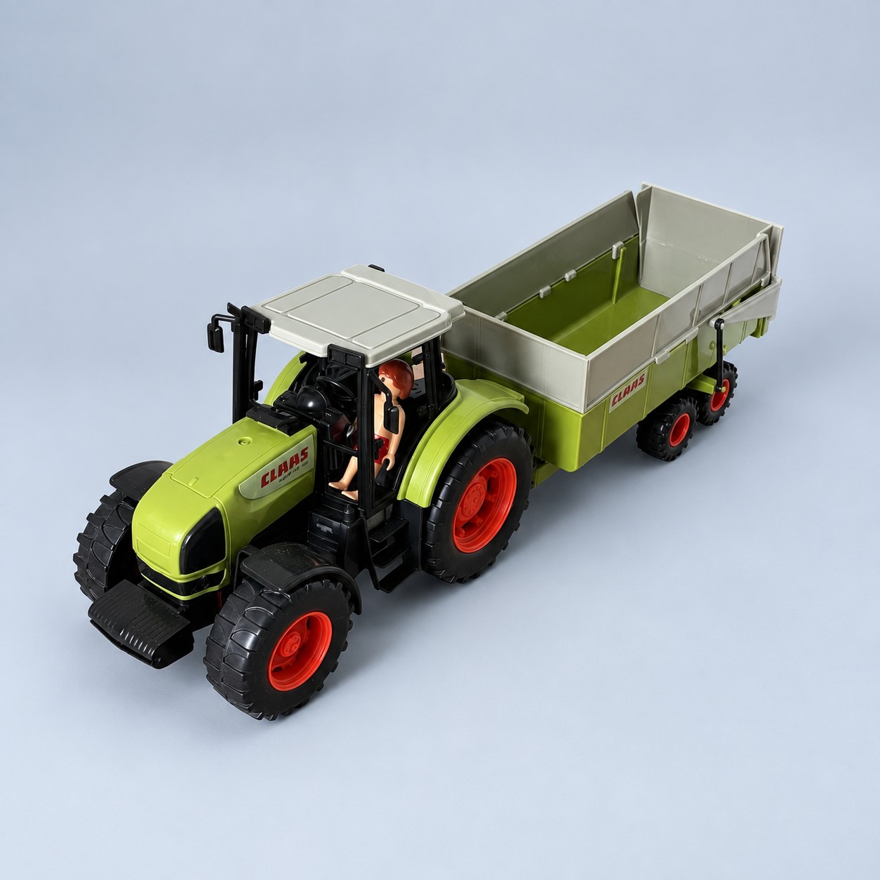 Zielony zabawkowy traktor CLAAS z przyczepą — aranżacja poglądowa AI na szaroniebieskim tle