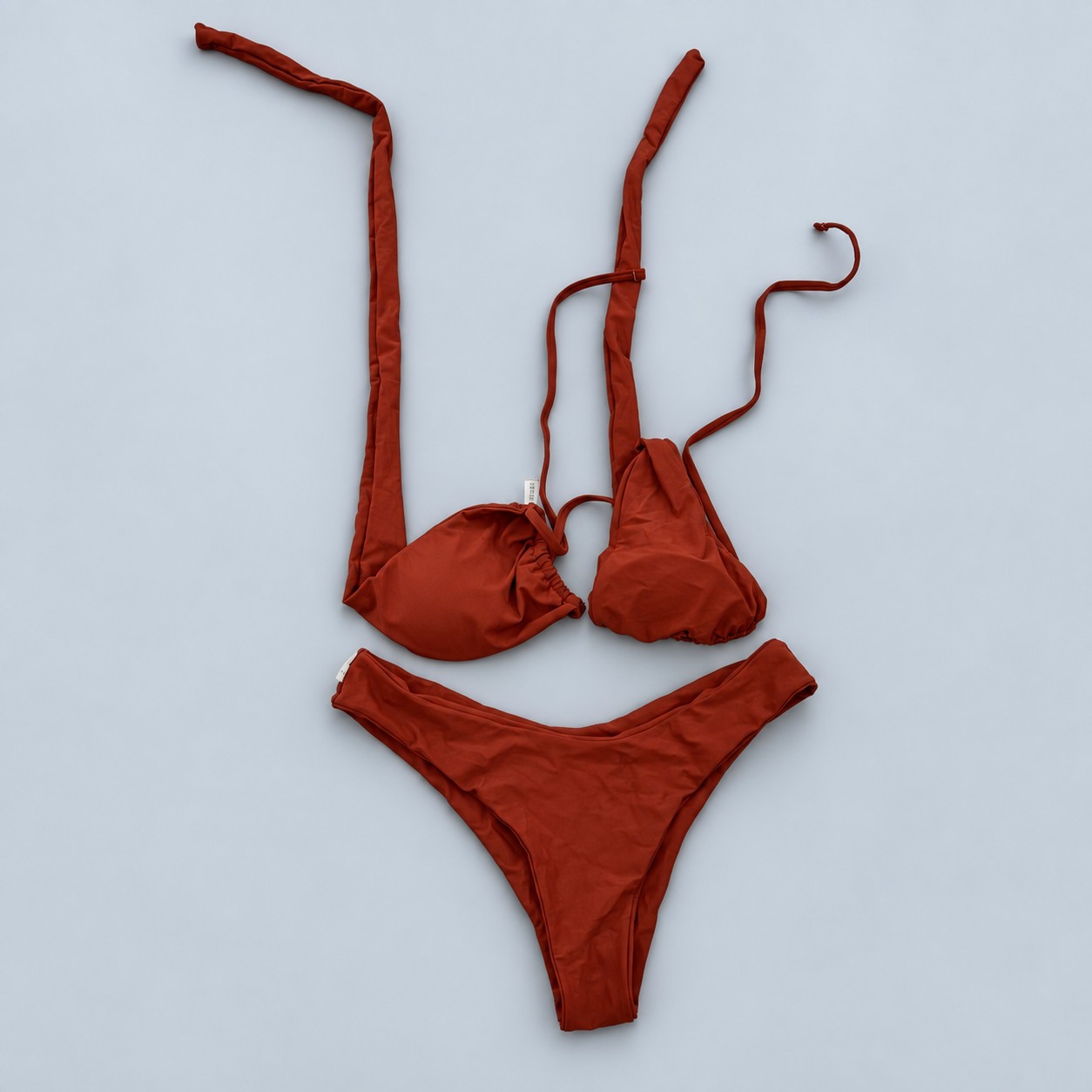 Bikini w rdzawym kolorze — aranżacja poglądowa AI na szaroniebieskim tle